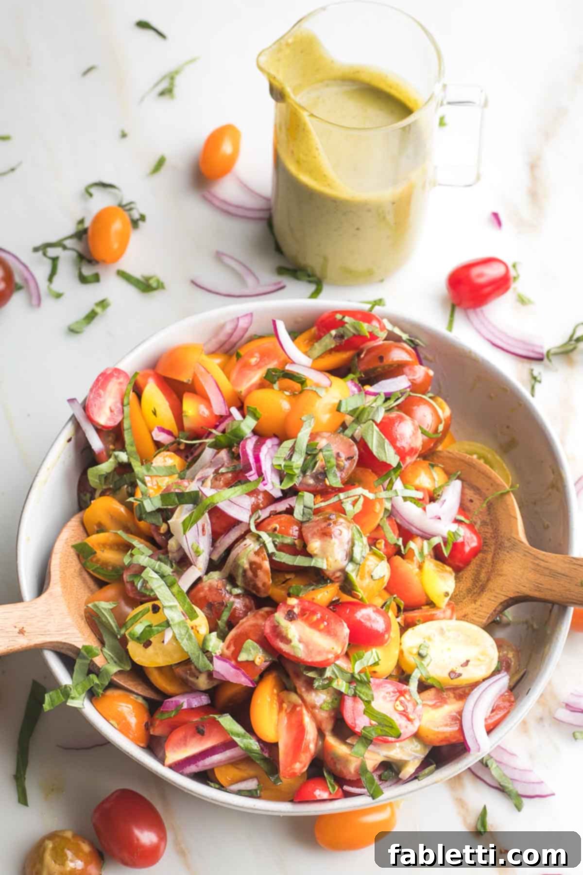 Sun-Kissed Tomato and Onion Salad with Balsamic Drizzle 8 Tomato and onion salad in a bowl with tossers and a pitcher of extra dressing.