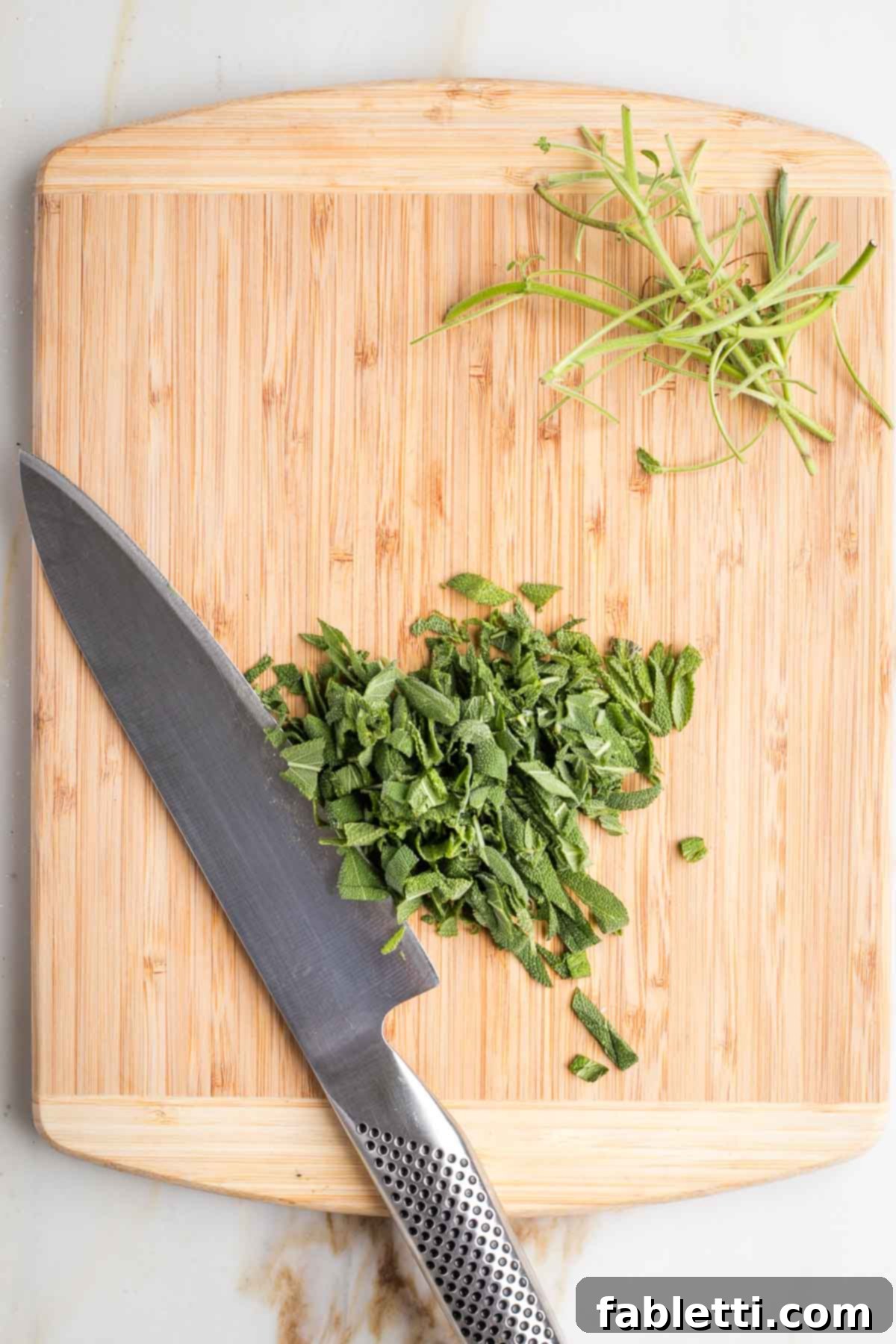 Fresh sage leaves stacked and roughly chopped, next to diced onions, celery, apples, and minced garlic.