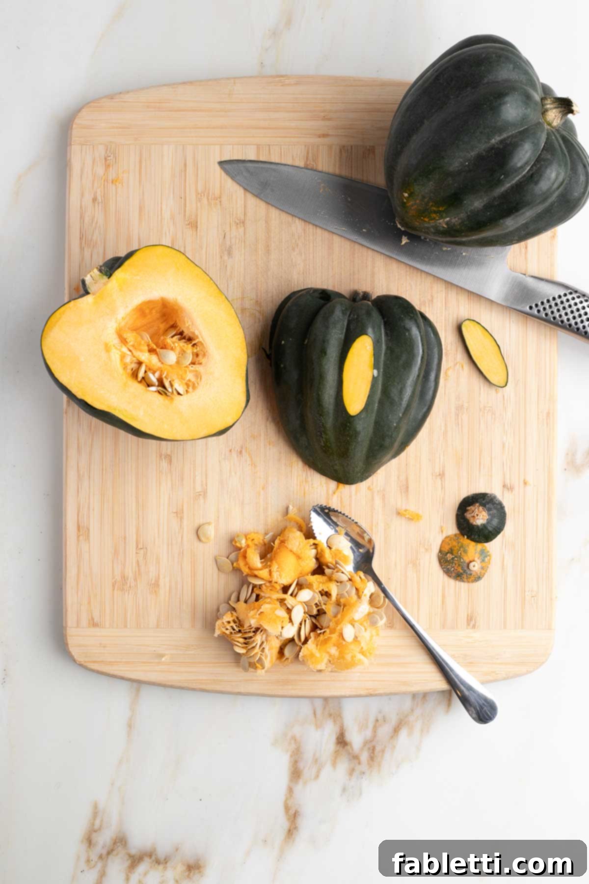 An acorn squash cut in half, showcasing the scooped-out seeds and strings, and a flat base allowing it to sit steadily.