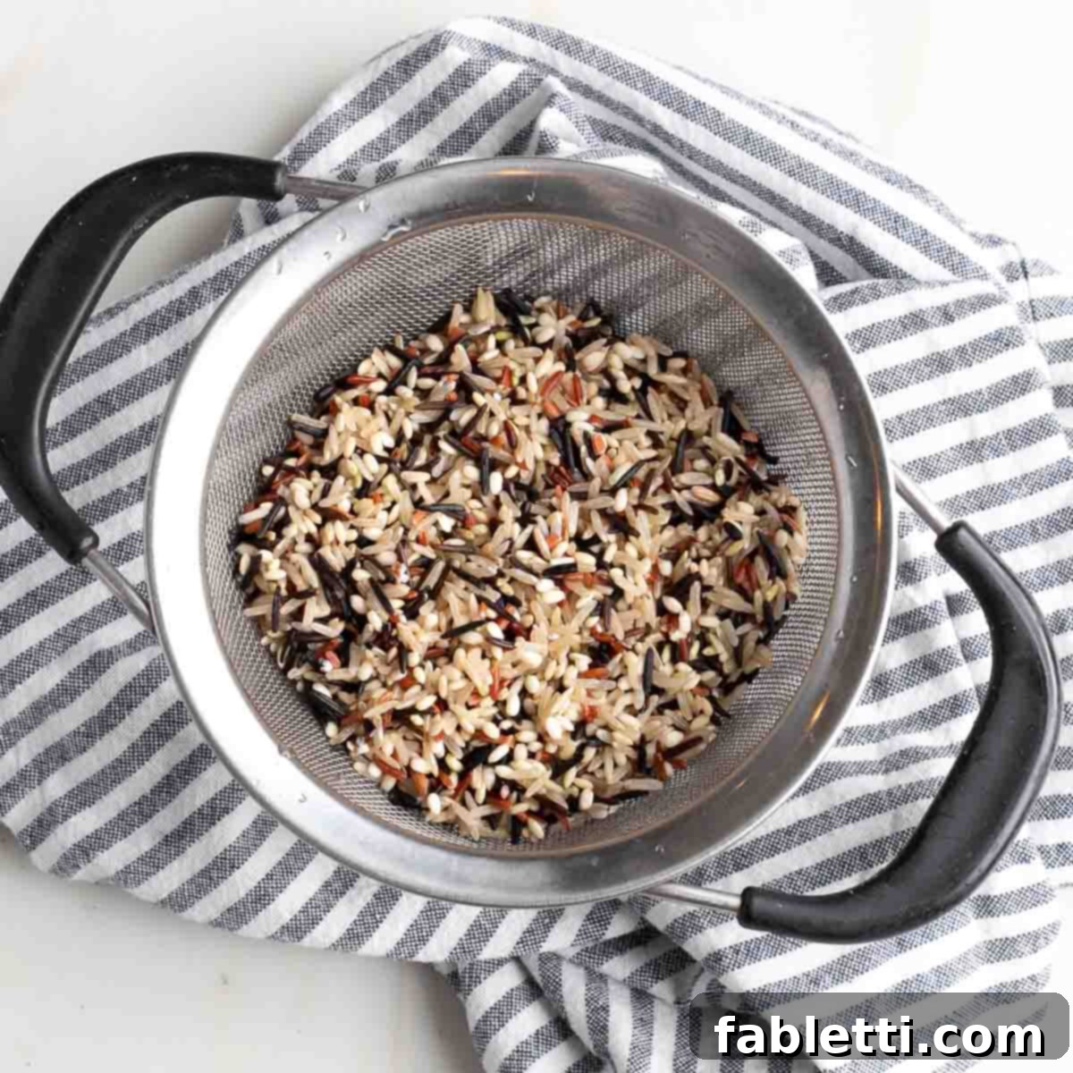 Wild rice being rinsed thoroughly under cool running water in a sieve.