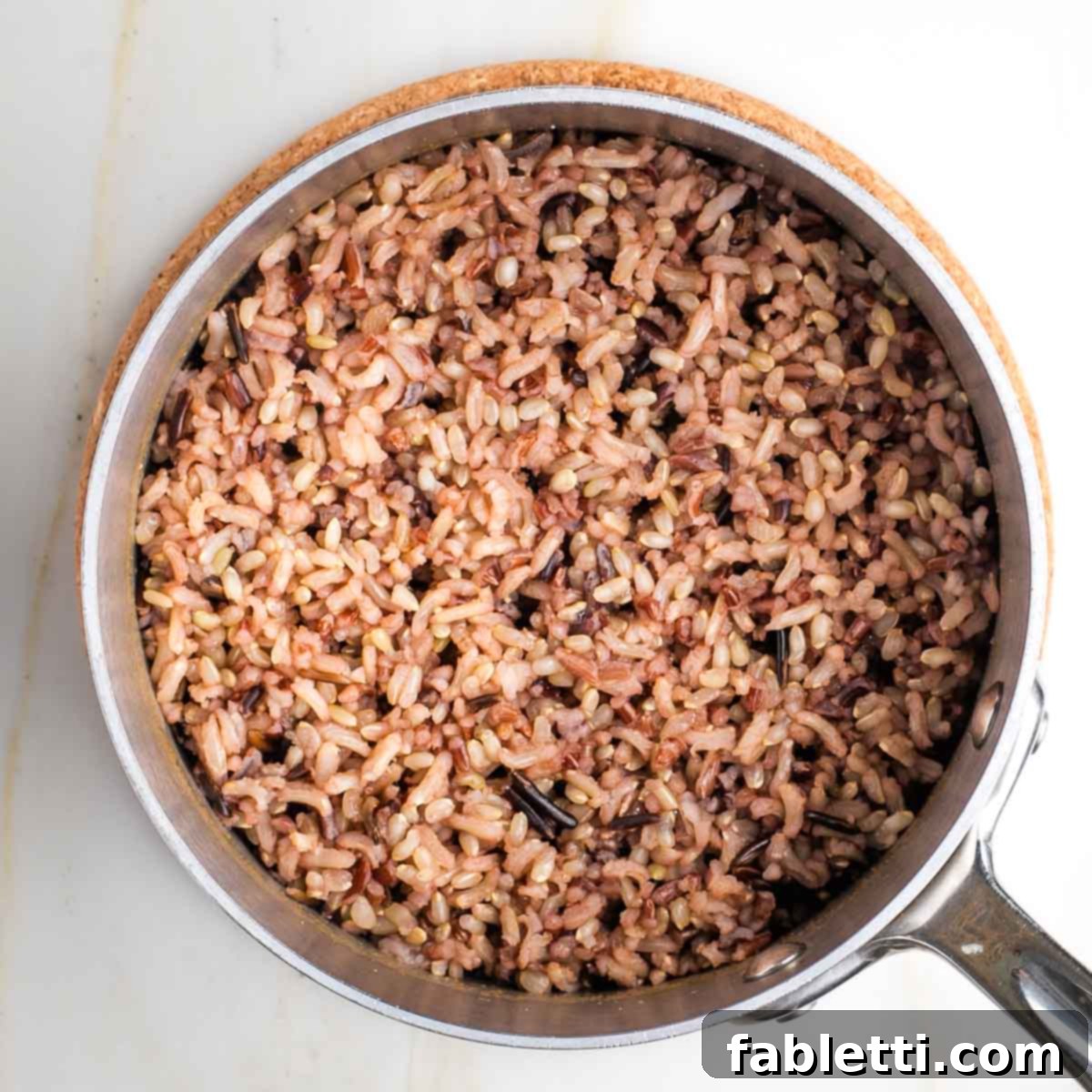 Wild rice simmering gently in a saucepan with vegetable broth, covered.