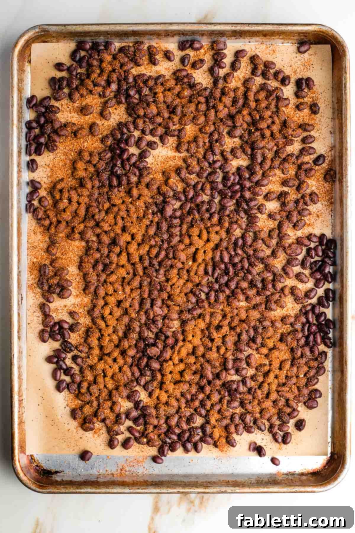 Crunchy Taco Black Beans 7 Sheet pan with black beans, generously sprinkled with taco seasoning. Ready for roasting.