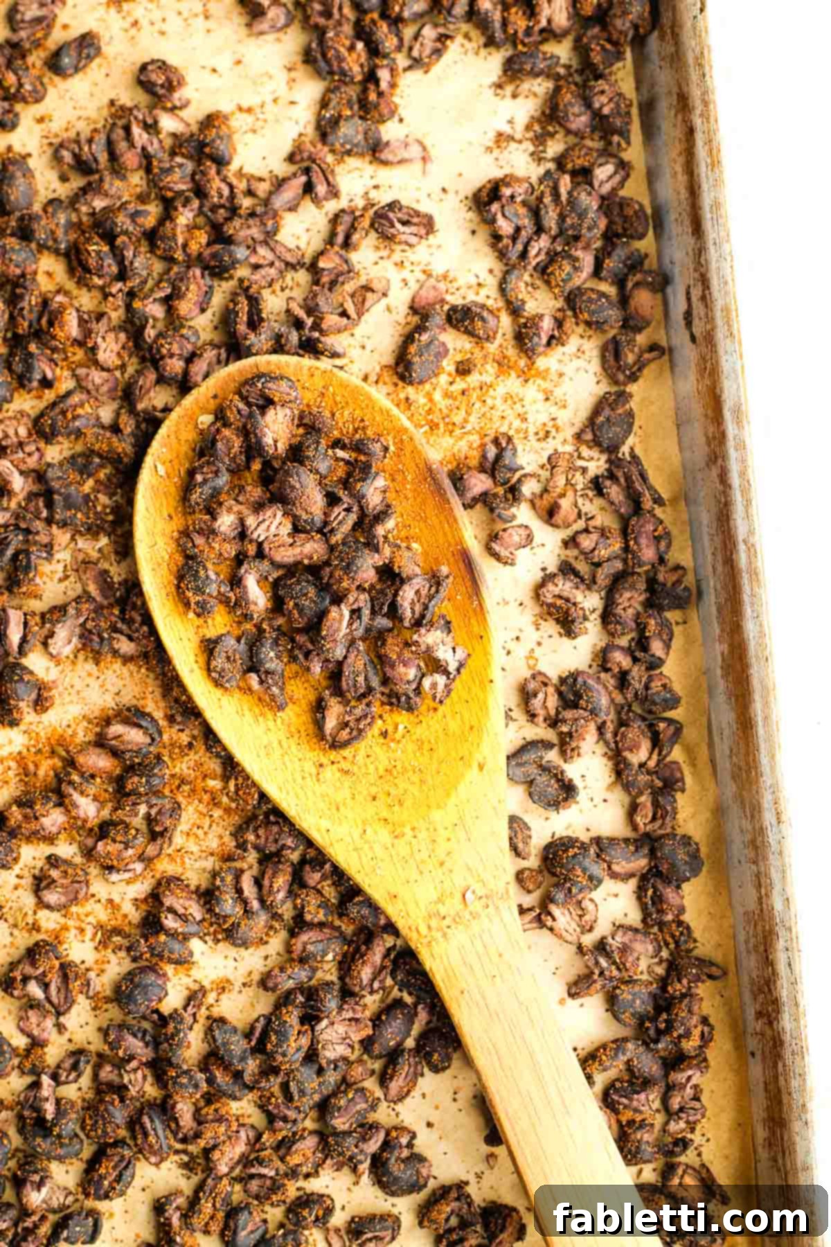 Crunchy Taco Black Beans 9 Wooden spoon showing close up of crispy black beans on a baking sheet. These beans are perfectly roasted and cracked.