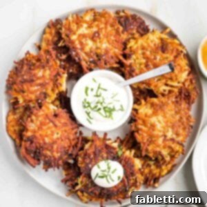 Grandma's Golden Potato Latkes 18 Crispy potato latkes beautifully arranged on a platter, with a small dish of tangy sour cream at the center for dipping.