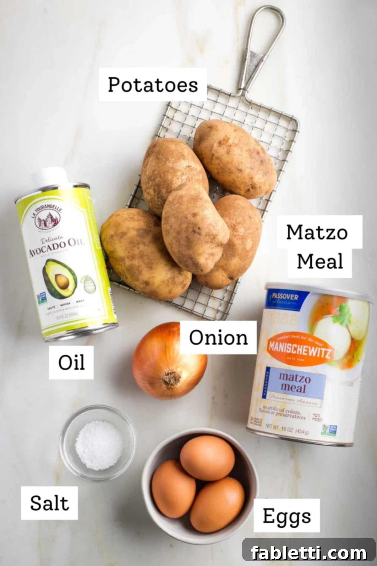 Grandma's Golden Potato Latkes 3 A selection of raw latke ingredients: large russet potatoes, a yellow onion, fresh eggs, and a bowl of matzo meal.