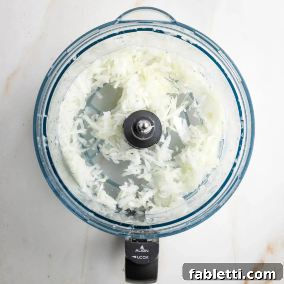 Grandma's Golden Potato Latkes 4 Shredded onions in the bowl of a food processor, ready to be mixed into the latke batter.
