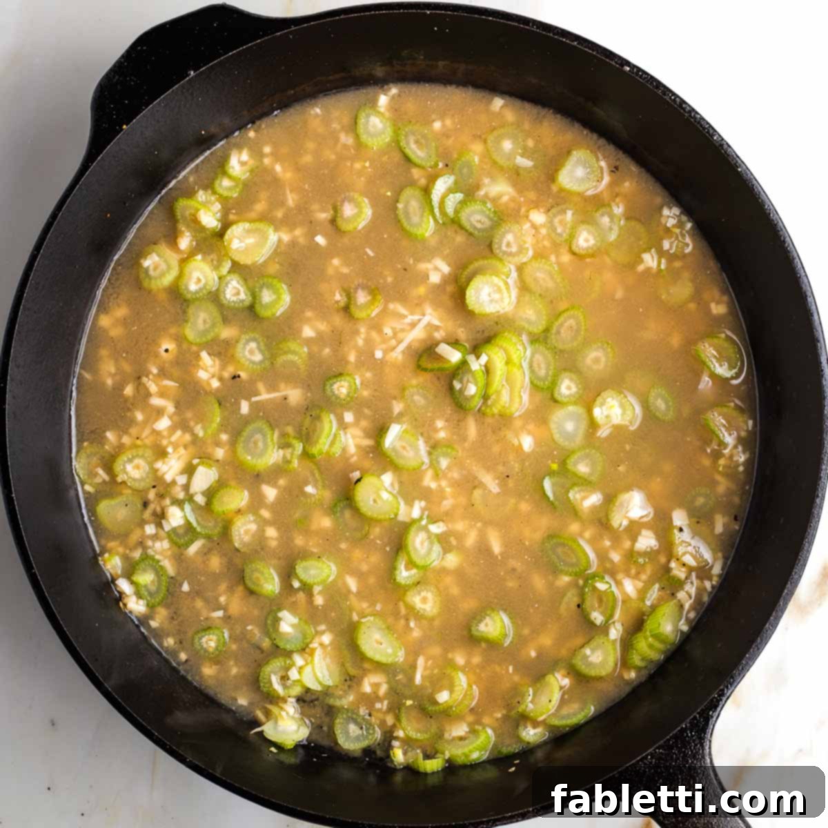 Vegetable broth being whisked with miso paste in a bowl, preparing it to be added to the braising liquid.