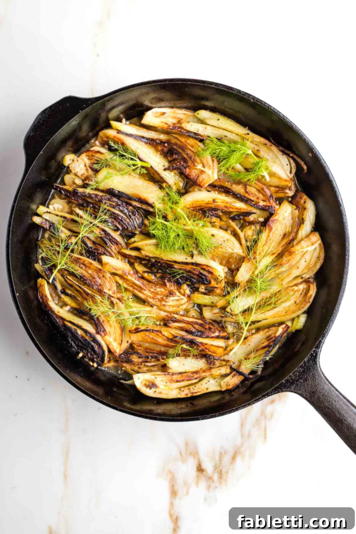 Succulent braised fennel wedges served on a platter, beautifully garnished with fresh fennel fronds, ready to be enjoyed.
