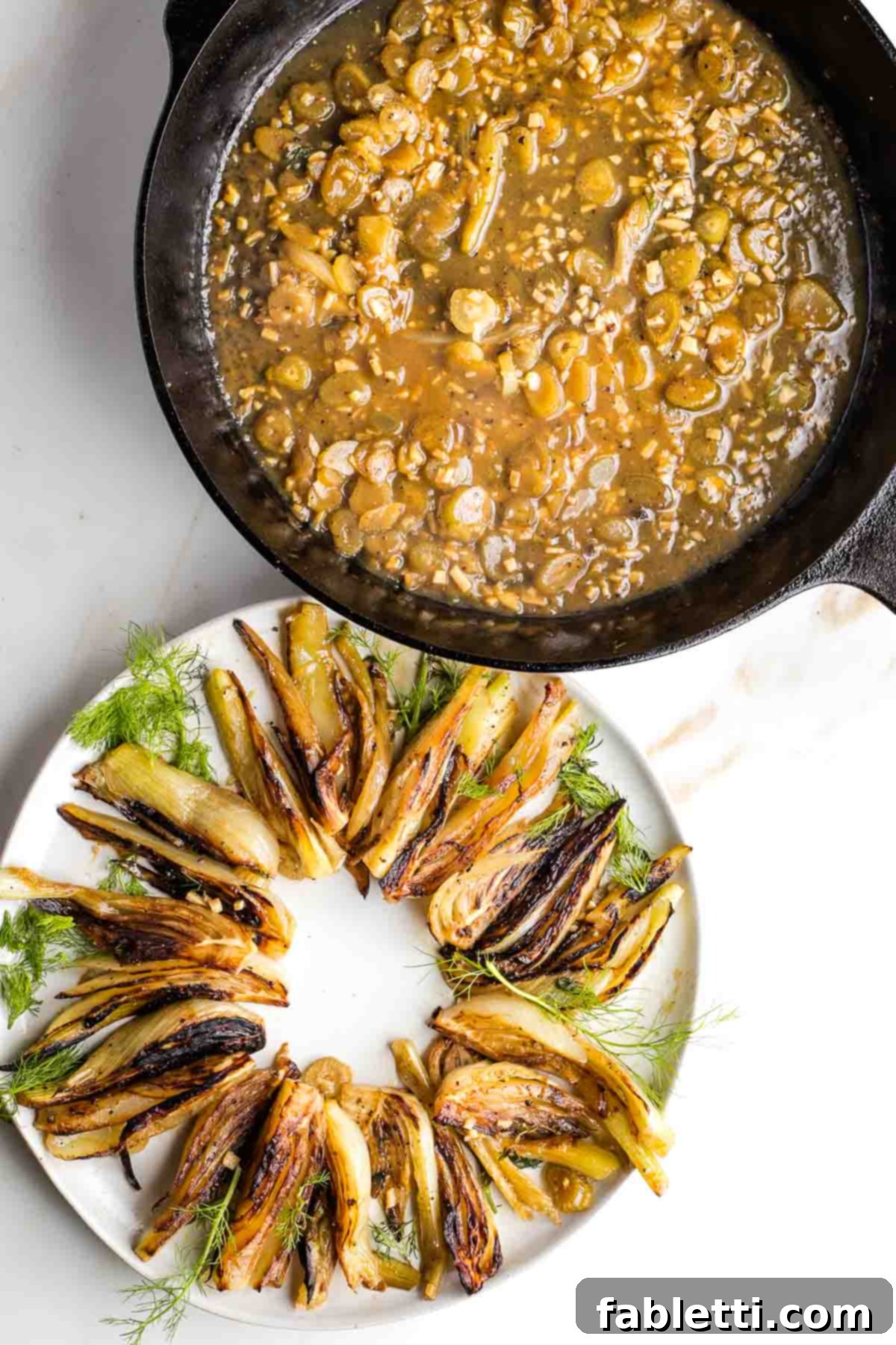 A cast iron skillet filled with rich, chunky sauce sits beside a platter adorned with browned fennel wedges, inviting guests to serve themselves.