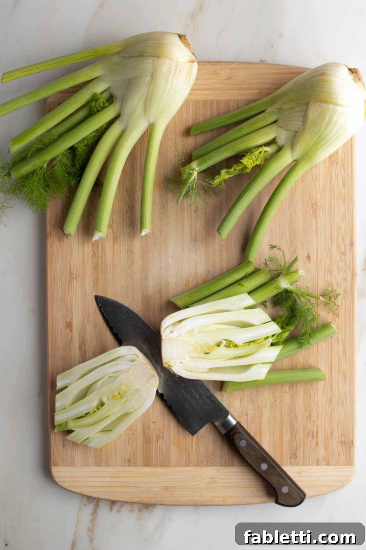 A crisp white fennel bulb precisely cut in half, revealing its central core.