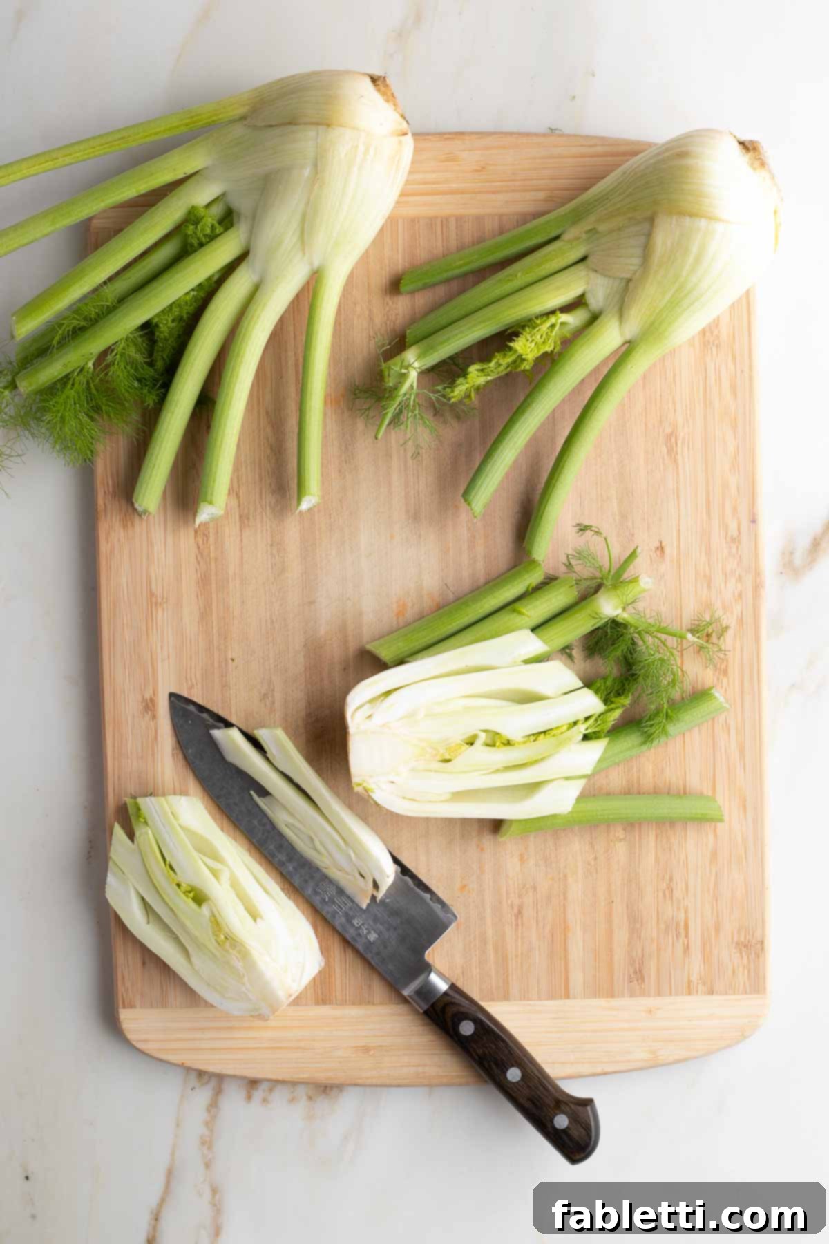 A fennel bulb being expertly cut into uniform wedges, with stalks and fronds separated.