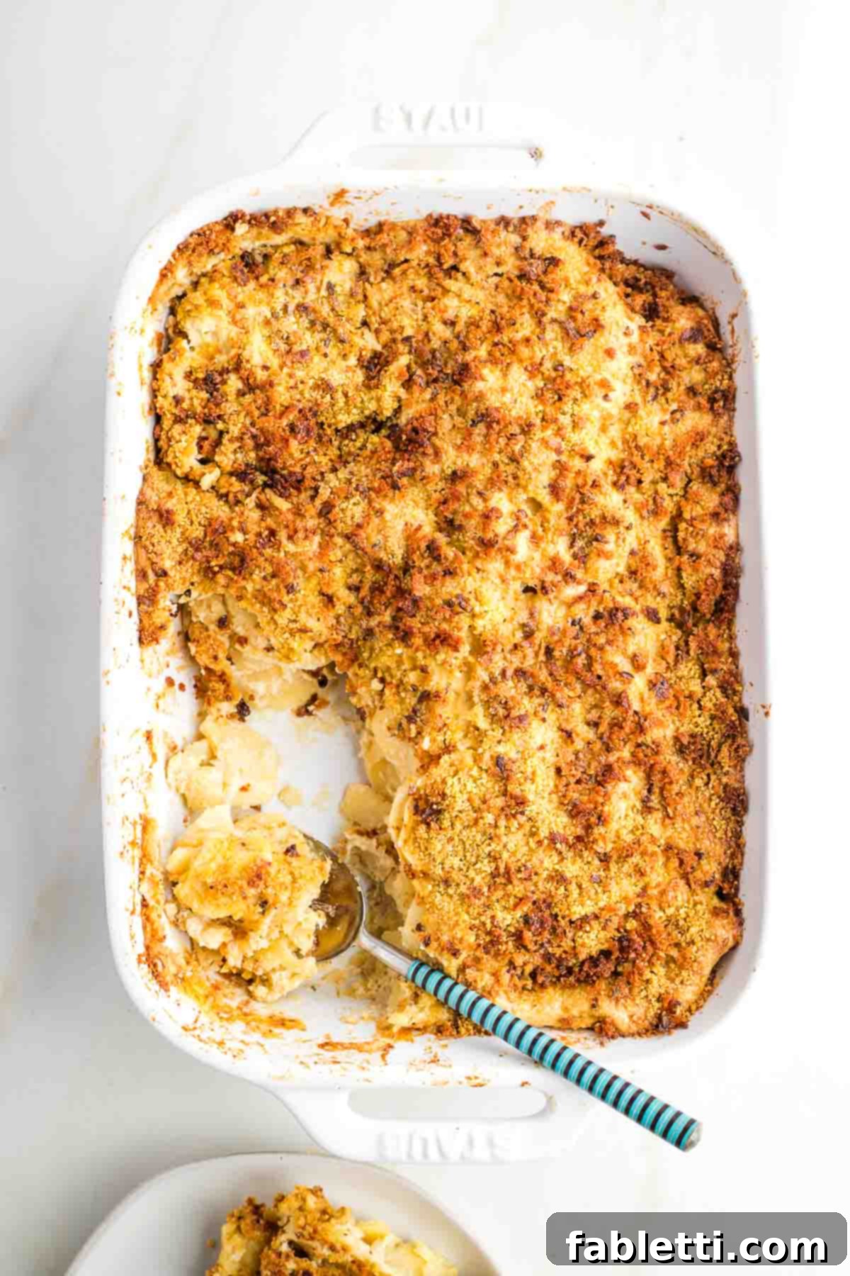 Luscious Vegan Parsnip Gratin 2 Thin discs of parsnip layered in a dish, covered in creamy sauce, topped with bread crumbs.