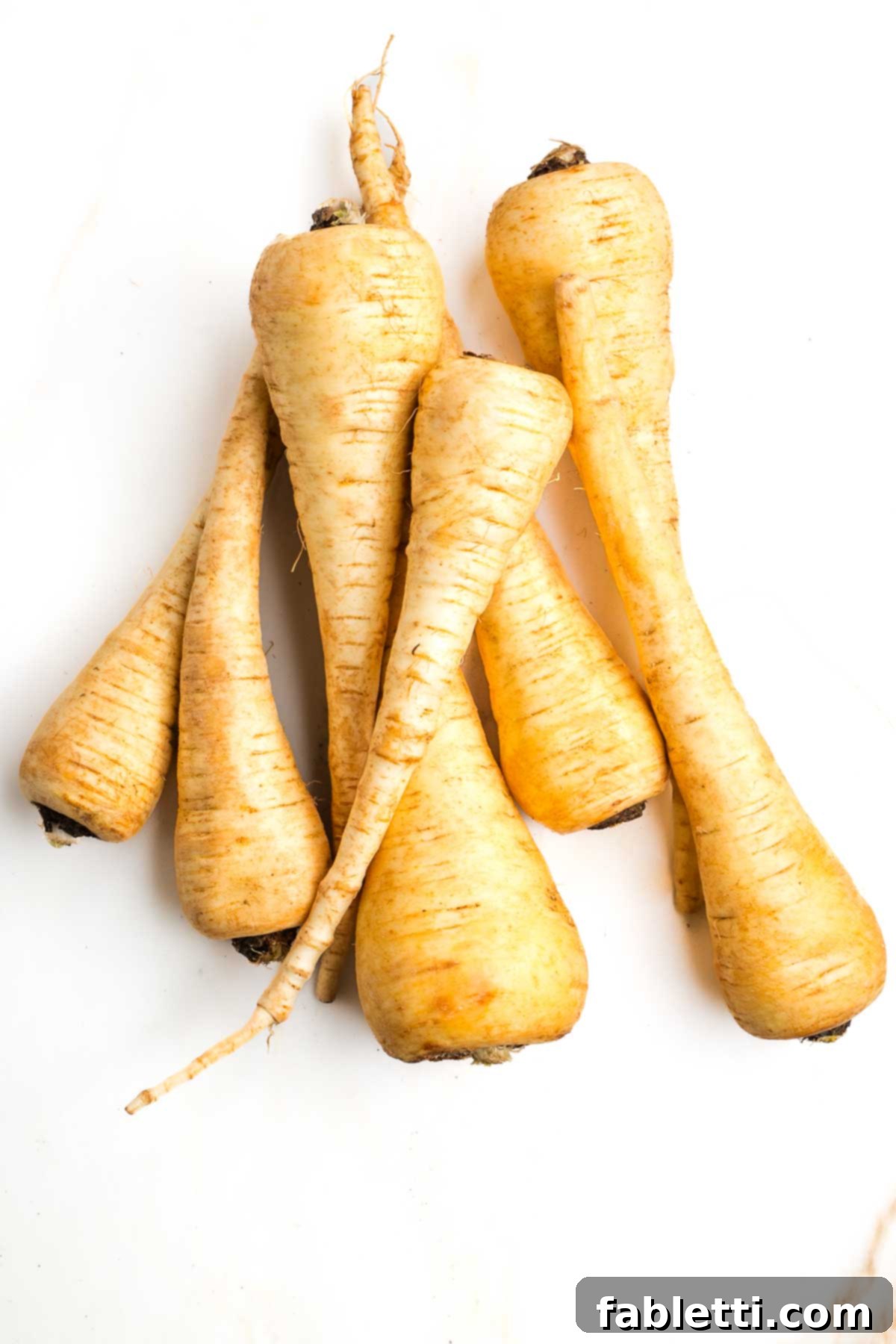 Luscious Vegan Parsnip Gratin 3 2 ½ pounds of parsnips stacked on a counter.