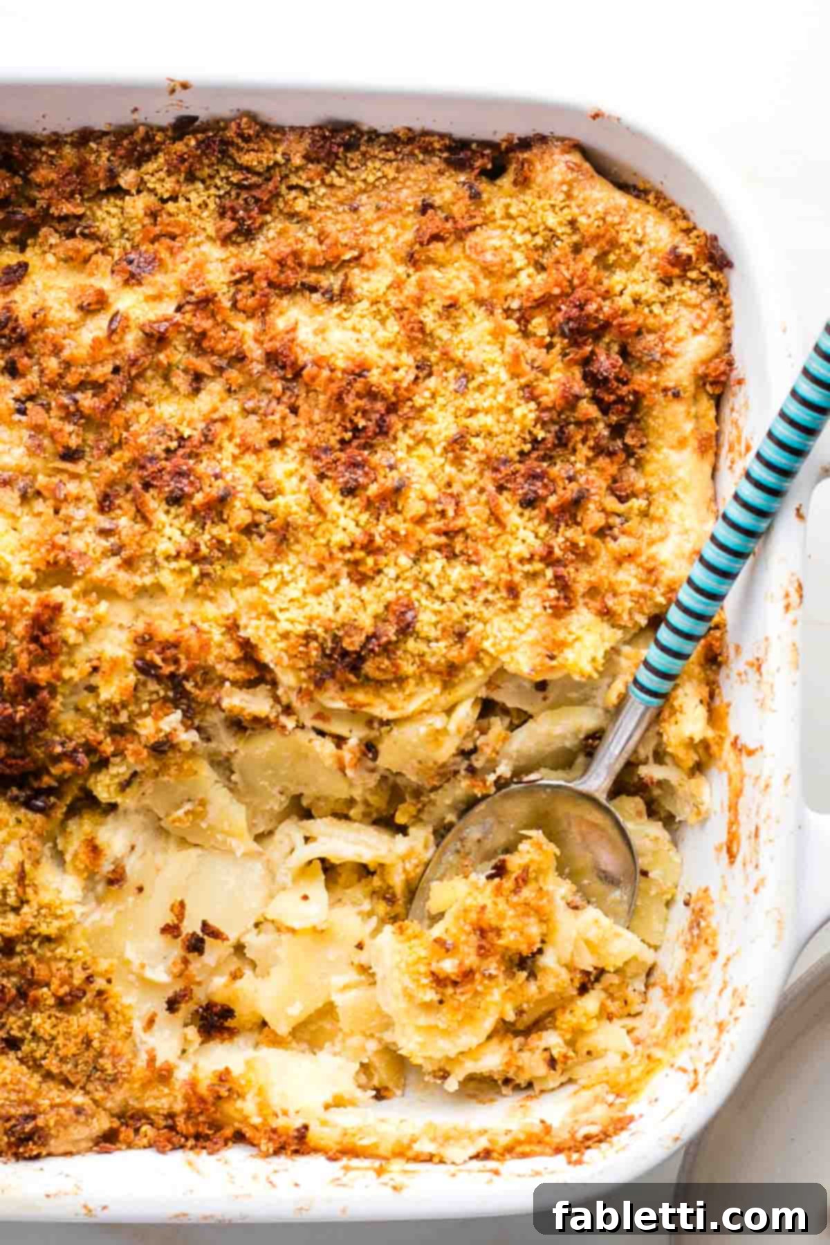 Luscious Vegan Parsnip Gratin 23 A slice of creamy parsnip gratin being scooped out of a baking dish.