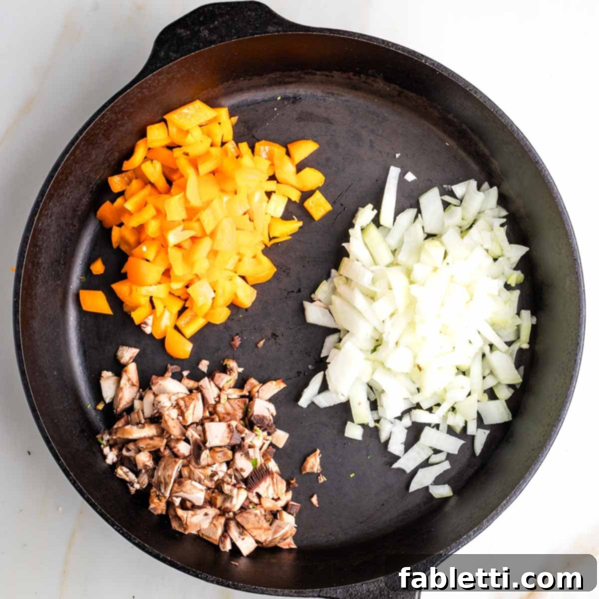 Gourmet Vegan Stuffed Portobello Mushrooms 11 Cast iron skillet with diced orange pepper, onion, and mushroom stems, beginning to sauté.