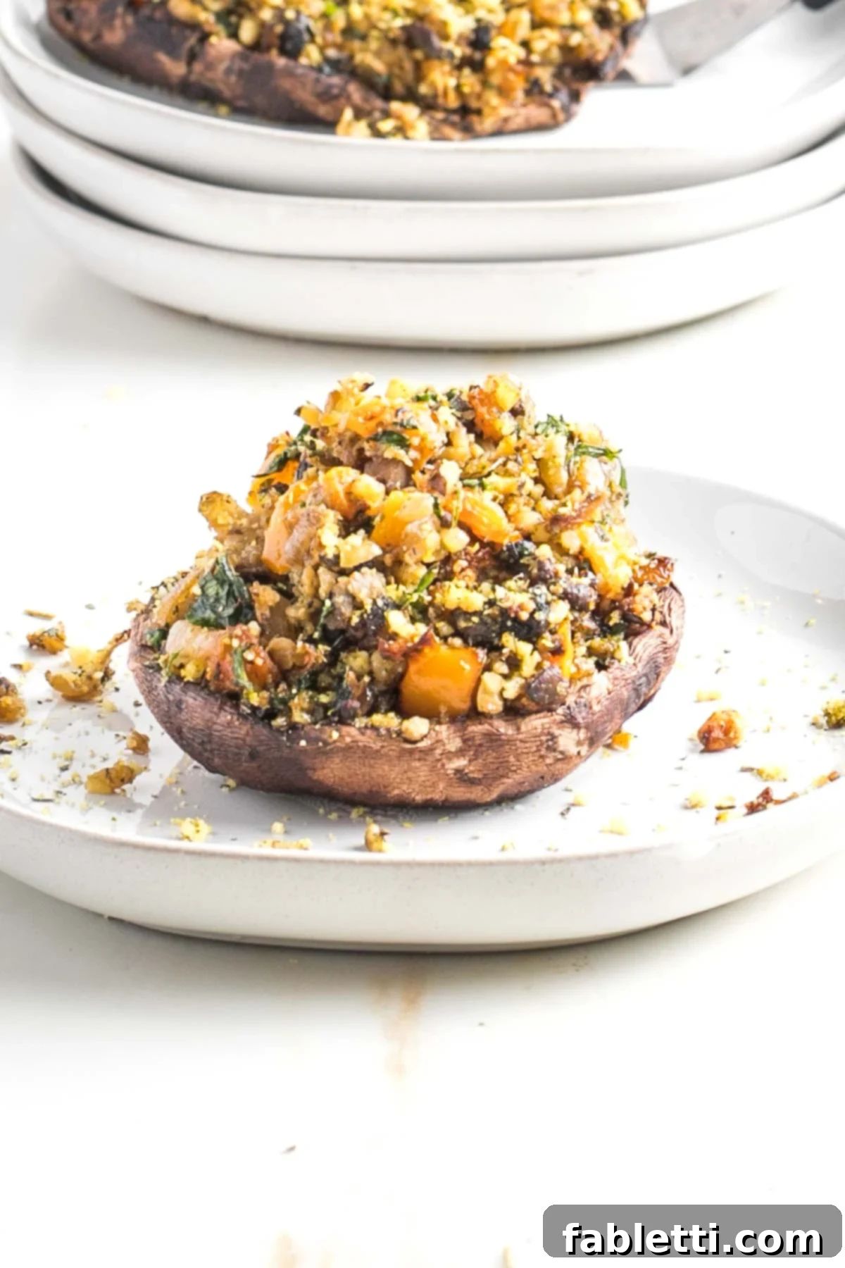 Gourmet Vegan Stuffed Portobello Mushrooms 18 Freshly baked vegan stuffed portobello mushroom, garnished with herbs on a dark plate.