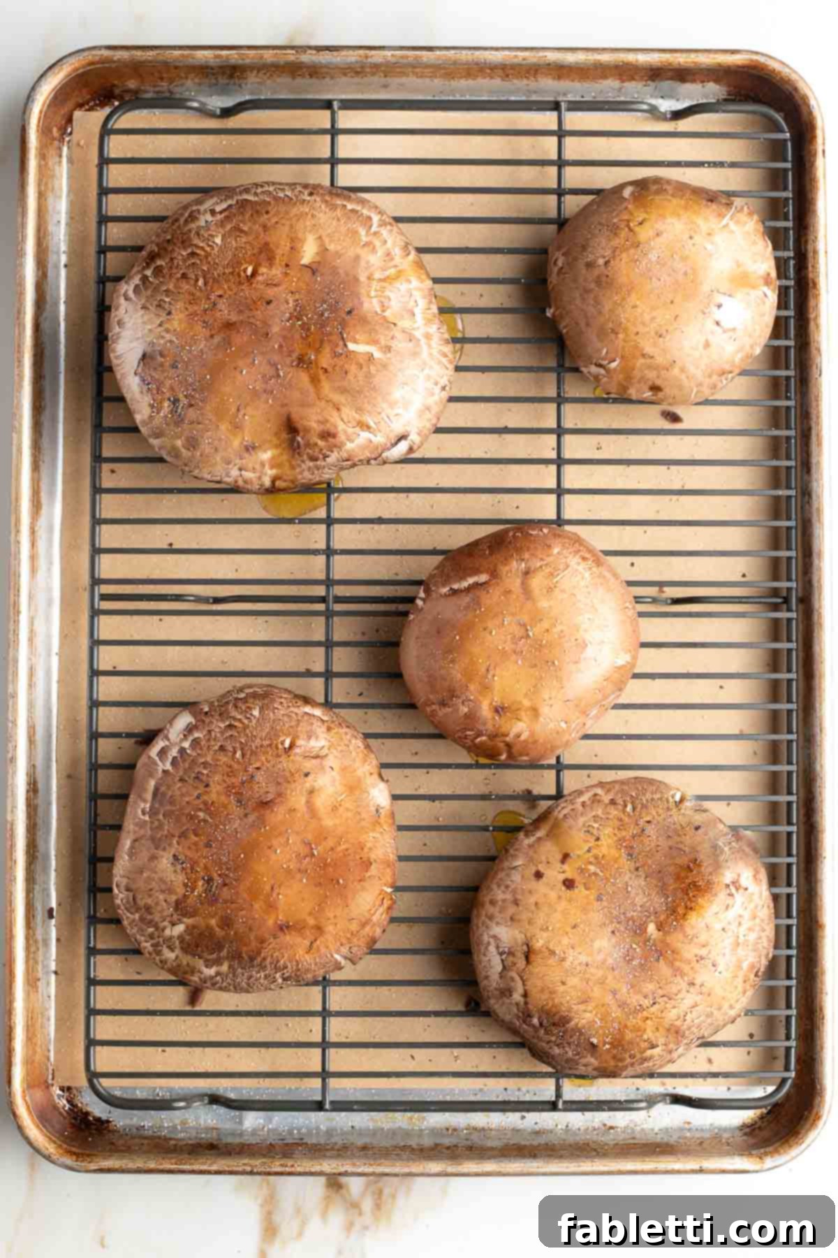 Gourmet Vegan Stuffed Portobello Mushrooms 7 Portobello mushroom caps on a wire rack placed on a baking tray, prepped for par-baking.