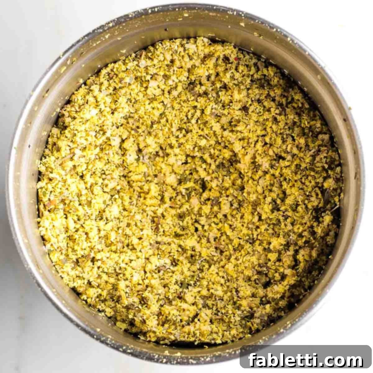 Gourmet Vegan Stuffed Portobello Mushrooms 10 A bowl of a spice grinder filled with coarse ground yellow powder, representing the finished vegan parmesan.