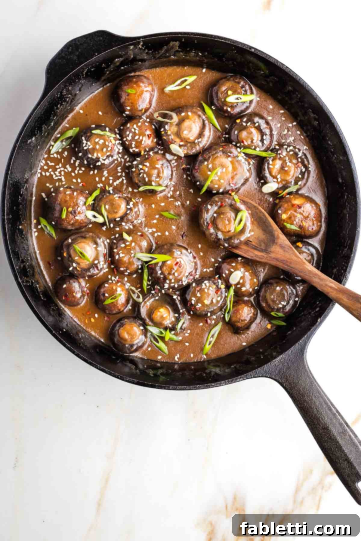 Umami-Rich Vegan Miso Mushrooms 11 Saucy mushrooms in cast iron skillet, garnished with sesame seeds, scallions and crushed red pepper.
