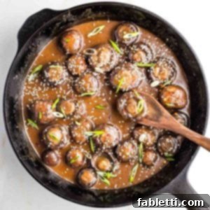 Umami-Rich Vegan Miso Mushrooms 15 Cast iron skillet filled with saucy mushrooms, sprinkled with scallions and sesame seeds.