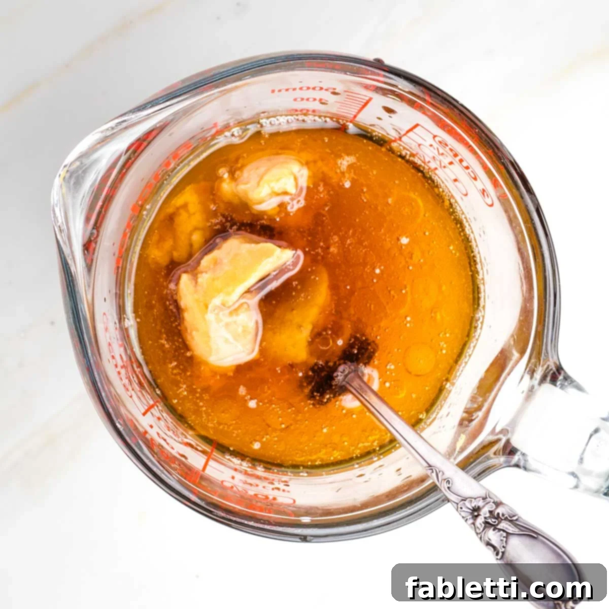 Umami-Rich Vegan Miso Mushrooms 4 Glass pitcher with brown liquid and a fork breaking up the miso paste.