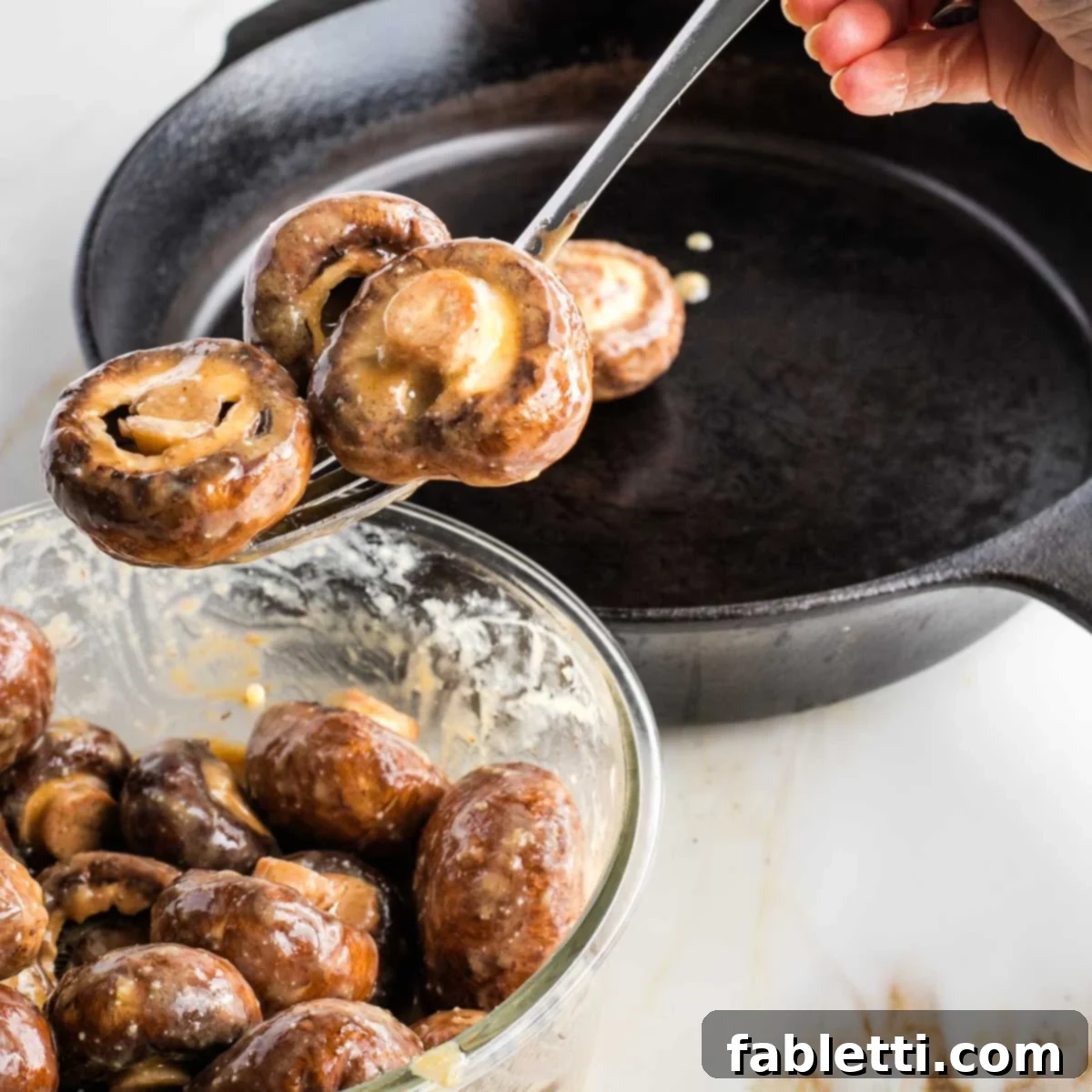 Umami-Rich Vegan Miso Mushrooms 8 Transferring marinated mushrooms to a hot cast iron skillet with a slotted spoon.