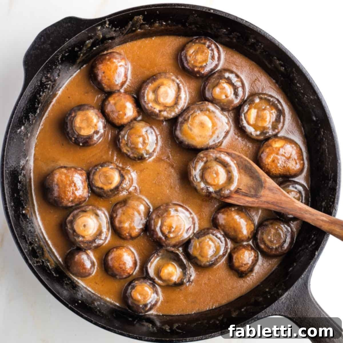 Umami-Rich Vegan Miso Mushrooms 10 Mushrooms in a thick, creamy brown sauce in a cast iron skillet.