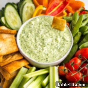 Vegan Tzatziki Sauce 13 Creamy green dip in a bowl, surrounded by colorful vegetables.
