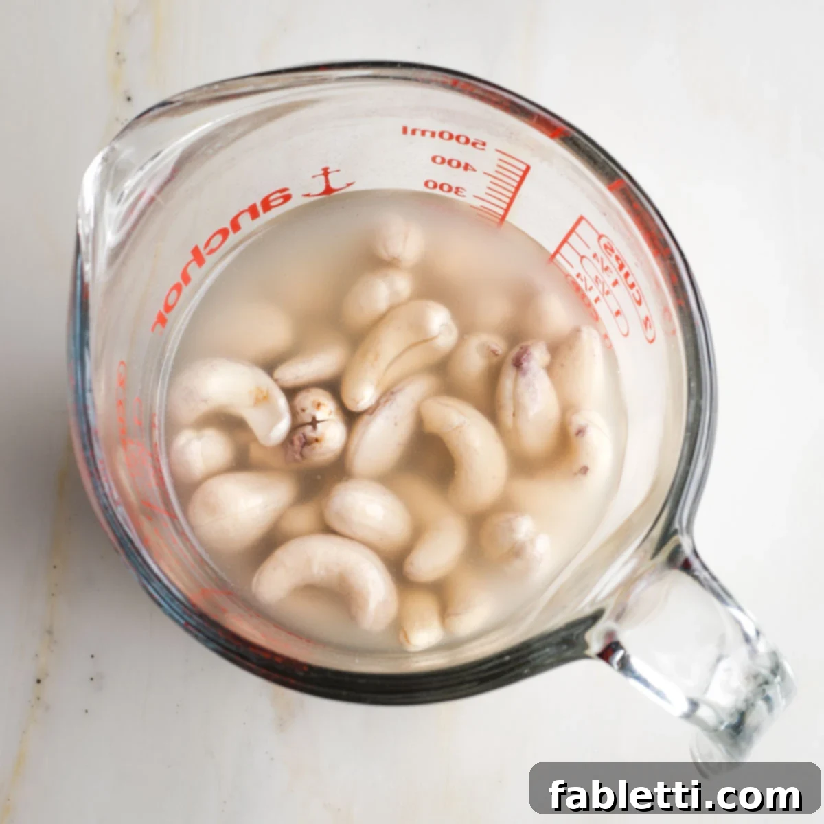 Vegan Tzatziki Sauce 4 Glass measuring cup with water covering raw cashews.