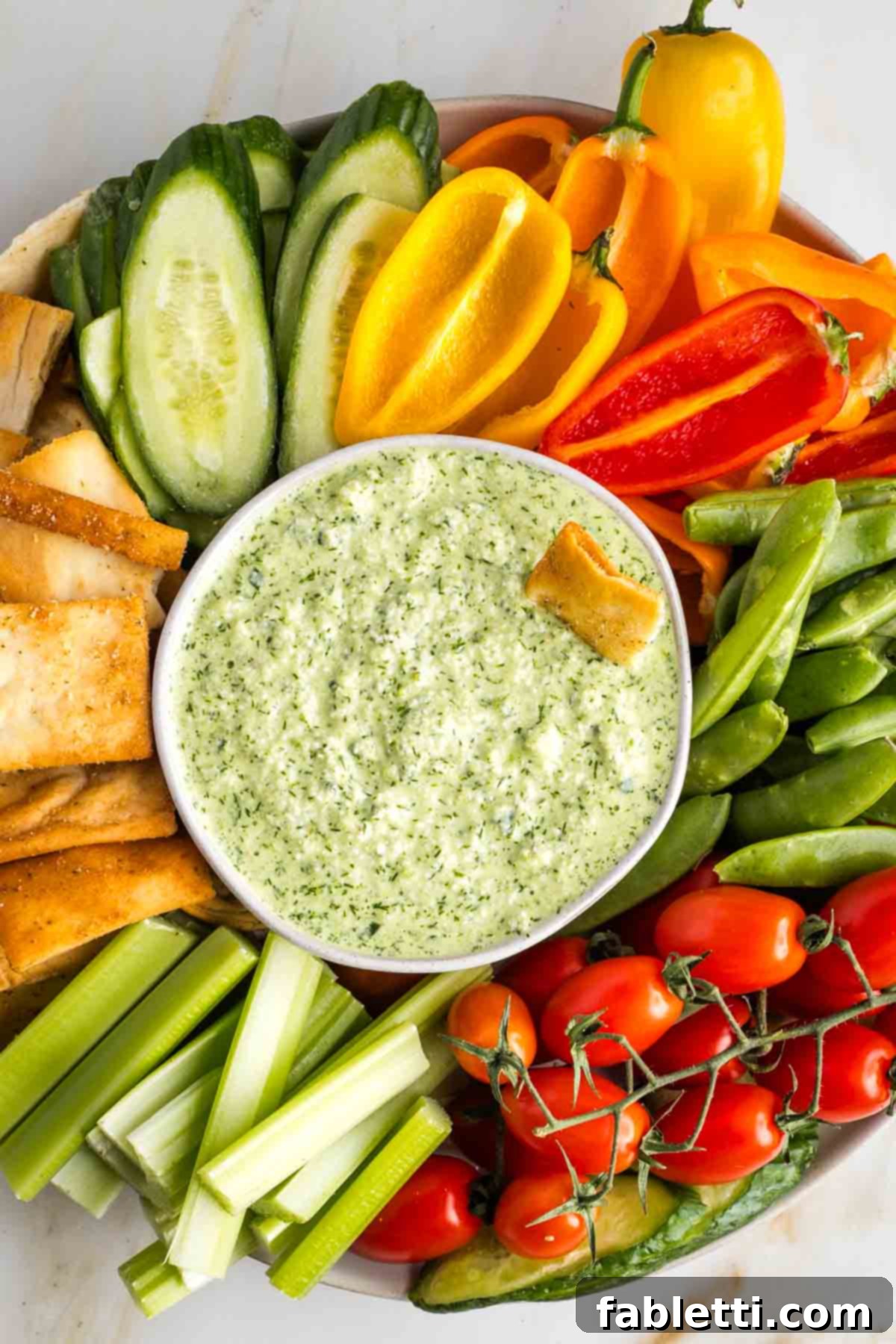 Vegan Tzatziki Sauce 9 Dairy free tzatziki in a bowl surrounded by colorful vegetables and pita chips.