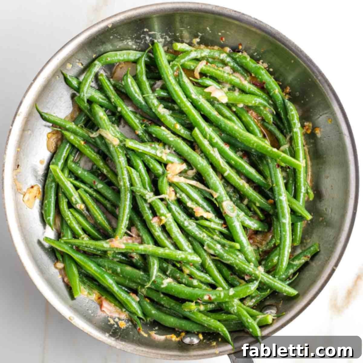 Zesty Green Bean Salad 12 A skillet filled with vibrant, saucy green beans, including some caramelized lemony shallots mixed throughout.