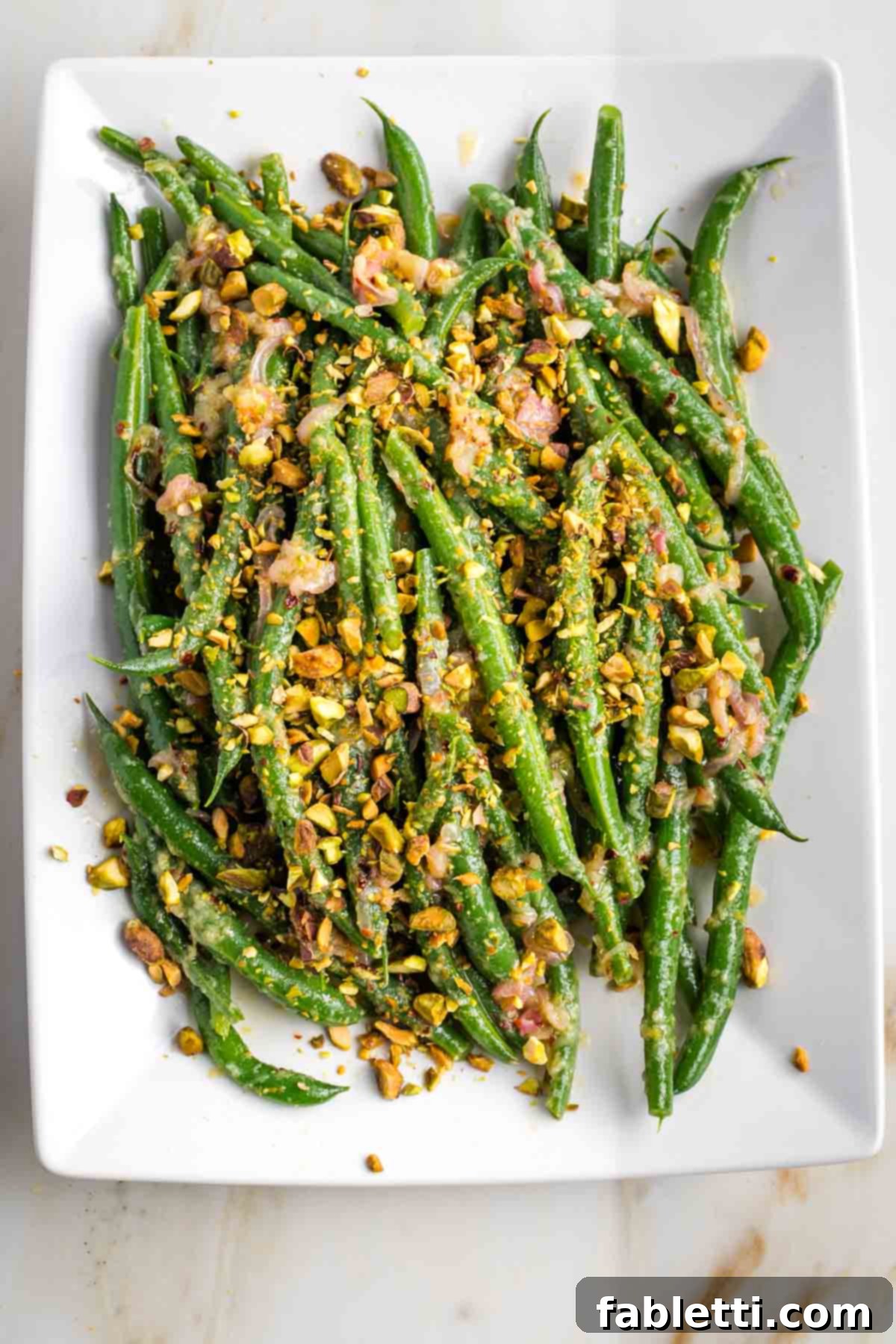 Zesty Green Bean Salad 14 Platter of Lemony Green Bean Salad with dressing and a final sprinkle of pistachios.