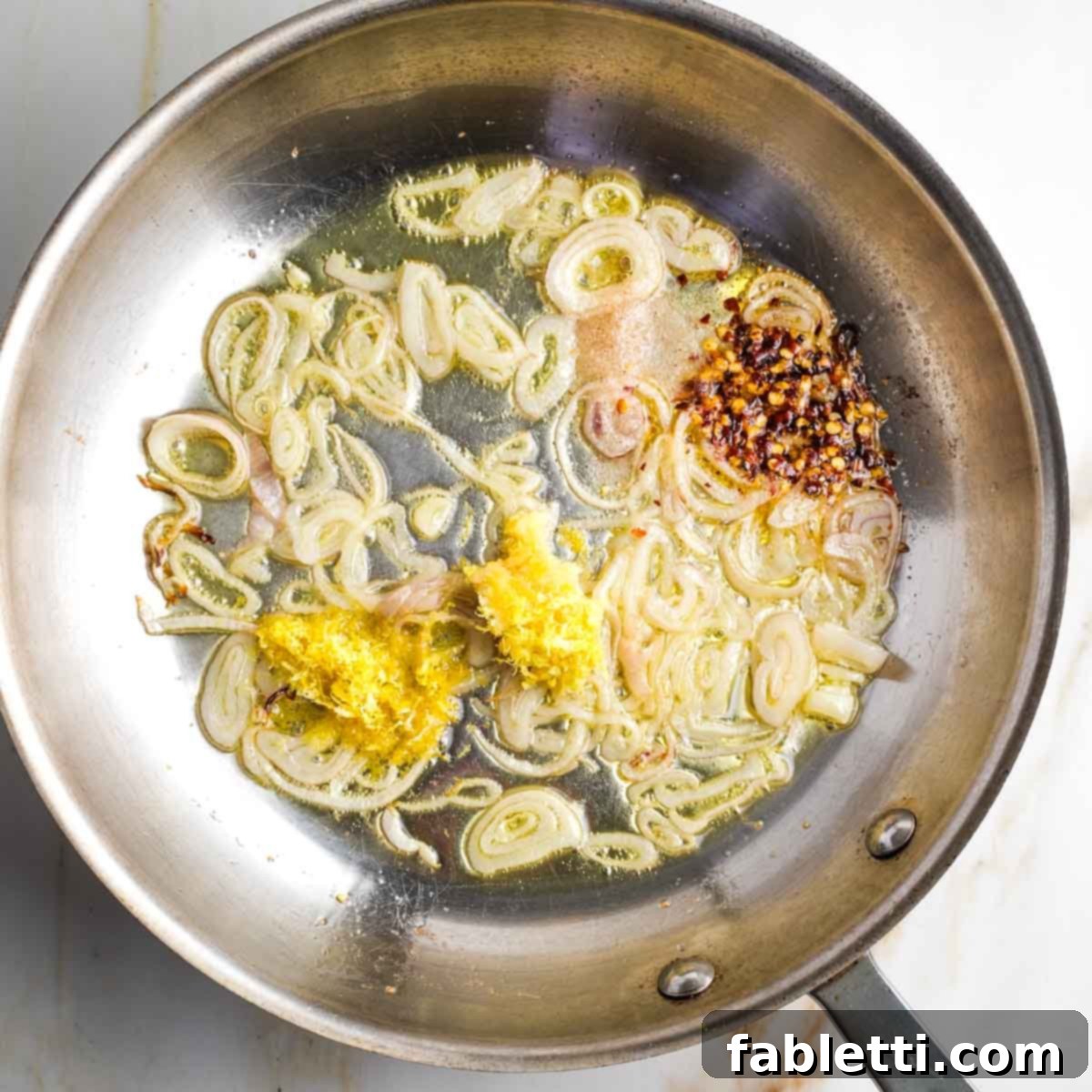Zesty Green Bean Salad 8 Sautéed shallots with lemon zest and garlic in a skillet, with a spoonful of Dijon mustard ready to be added.