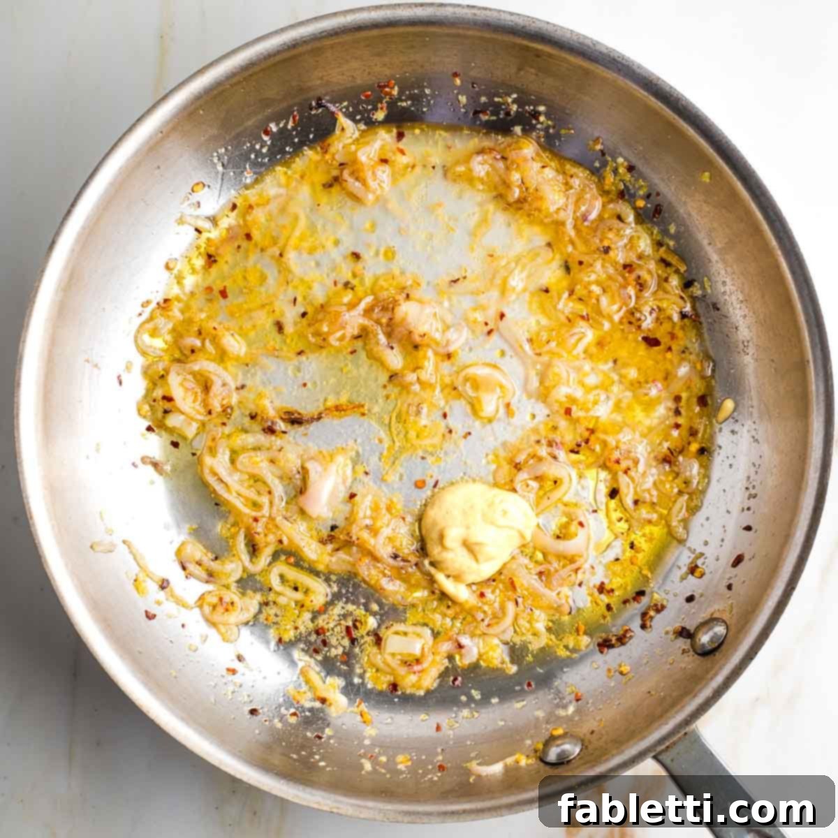 Zesty Green Bean Salad 9 A fry pan containing sautéed shallots, garlic, and lemon zest, now with Dijon mustard added.