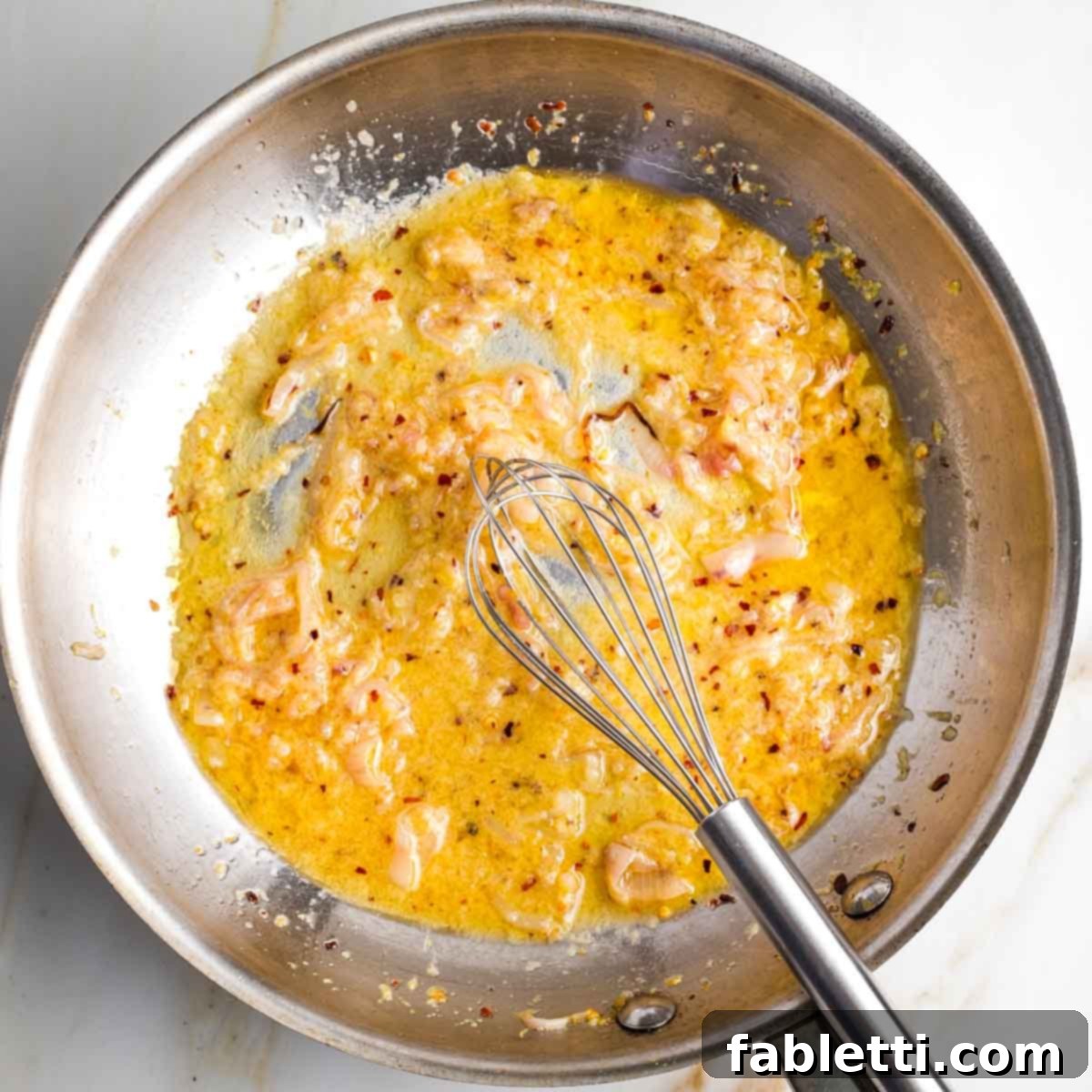 Zesty Green Bean Salad 10 A whisk vigorously mixing the lemony mustard sauce with shallots in a skillet.