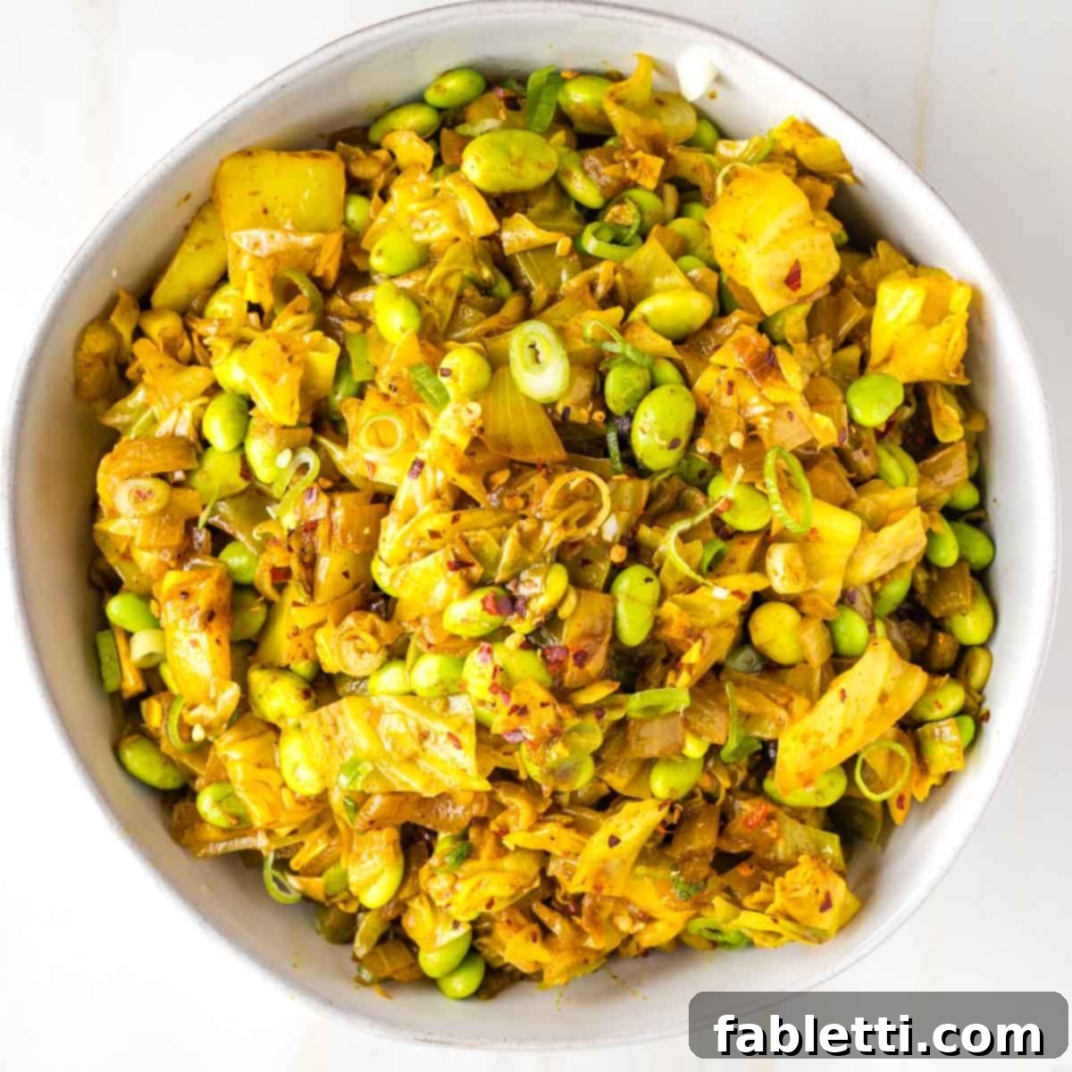 Speedy Skillet Curried Cabbage 11 Cooked cabbage chunks with edamame, scallions and crushed red pepper in a serving bowl.