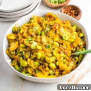 Speedy Skillet Curried Cabbage 12 Bowl full of chopped cabbage with onions and edamame in a yellow curry, garnished with sliced scallions.