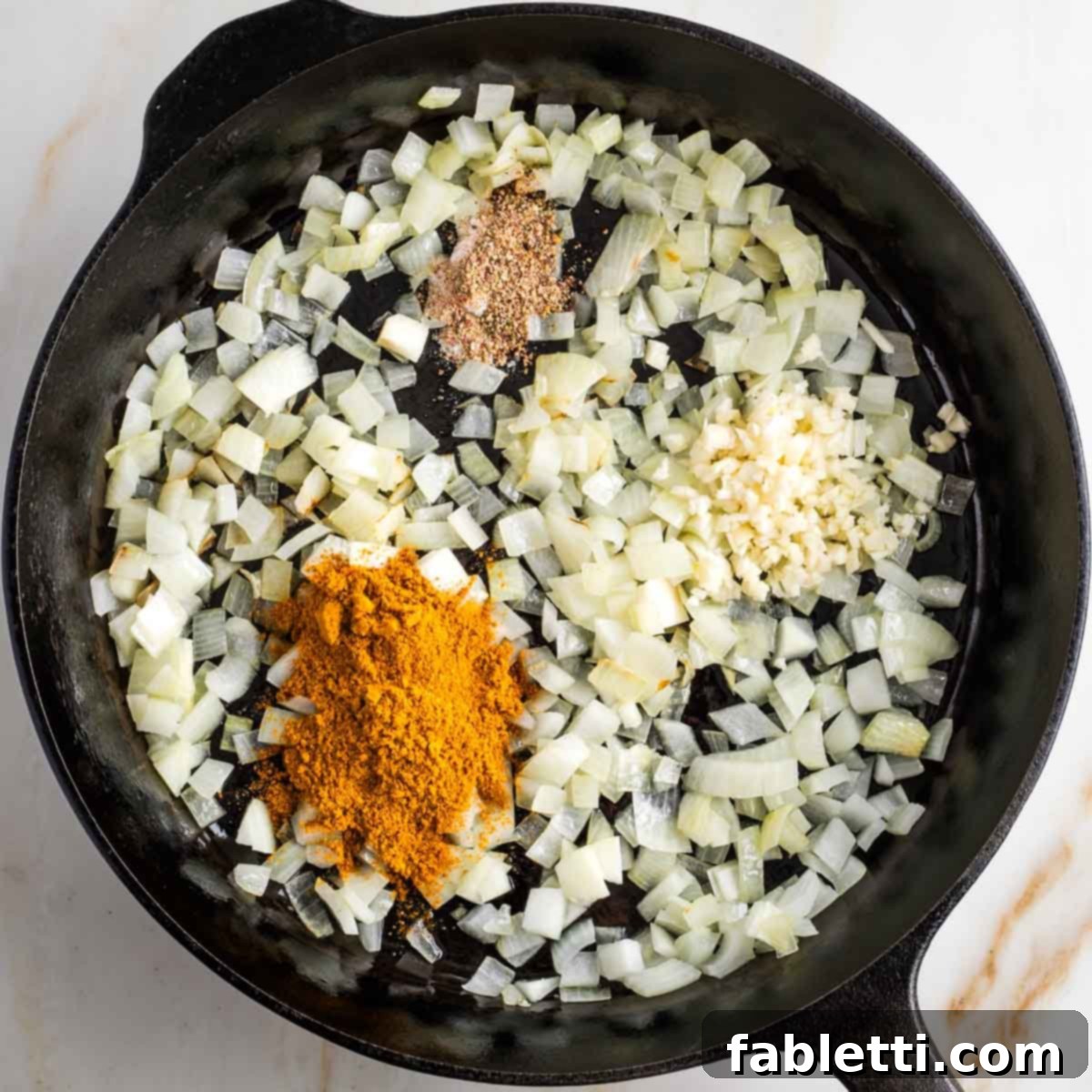 Speedy Skillet Curried Cabbage 4 Sauteed onions in a cast iron skillet with curry powder, salt and pepper and minced garlic on top.