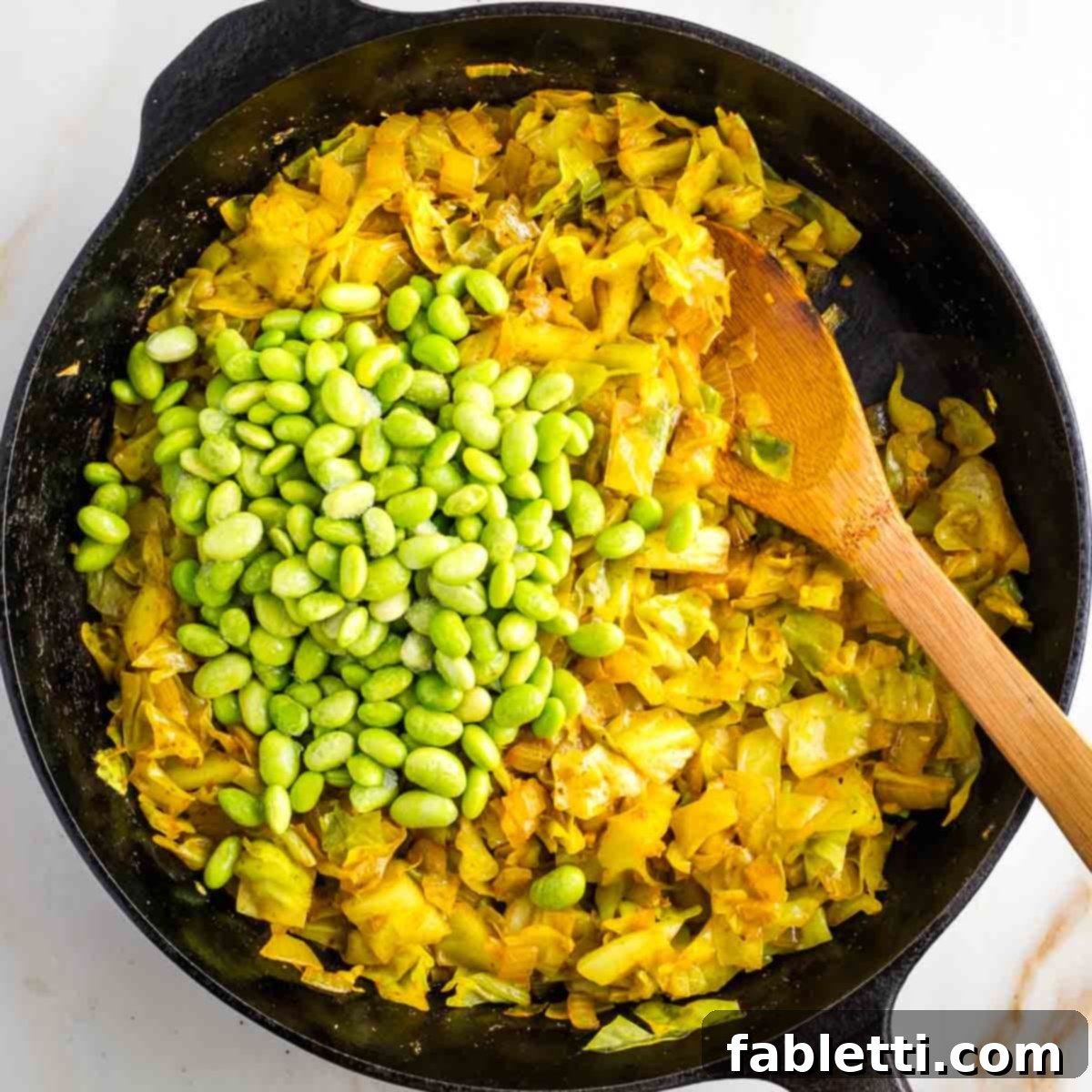 Speedy Skillet Curried Cabbage 8 Adding shelled frozen edamame to a pan of cooked chopped cabbage.