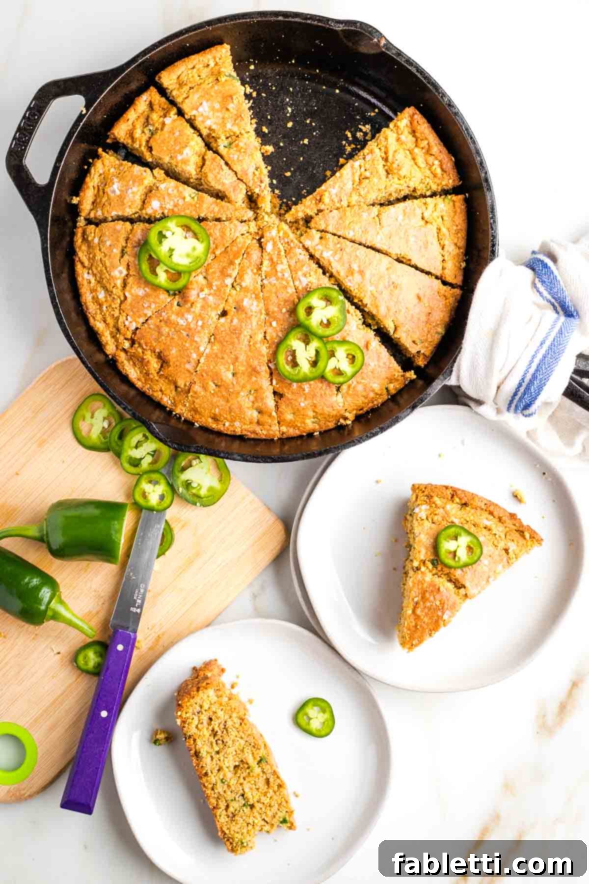 Spicy Vegan Skillet Jalapeño Cornbread 2 Skillet cornbread cut into pie slices with jalapenos on top and on the plated pieces.
