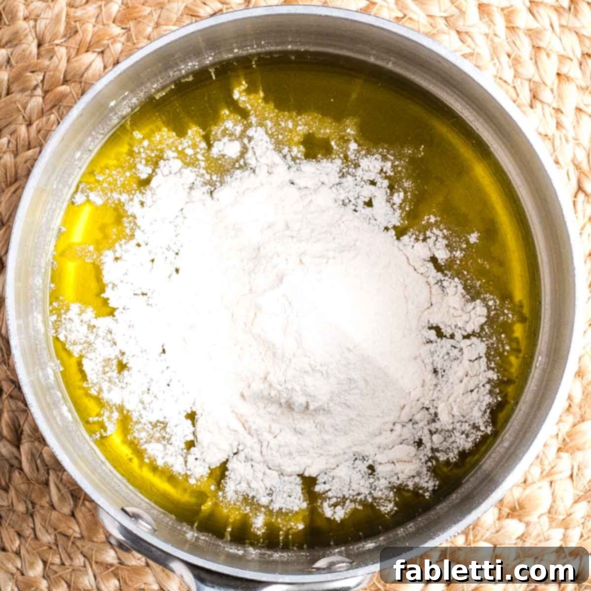 Silky Vegan Bechamel 4 Flour sprinkled on top of olive oil in a small saucepan.