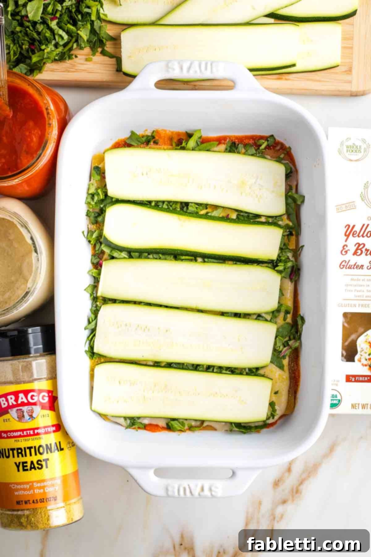 Lush Layers: Gluten-Free Vegan Garden Lasagna 11 Thinly sliced zucchini topping layers of noodles and sauce in the making of a vegetable lasagna.