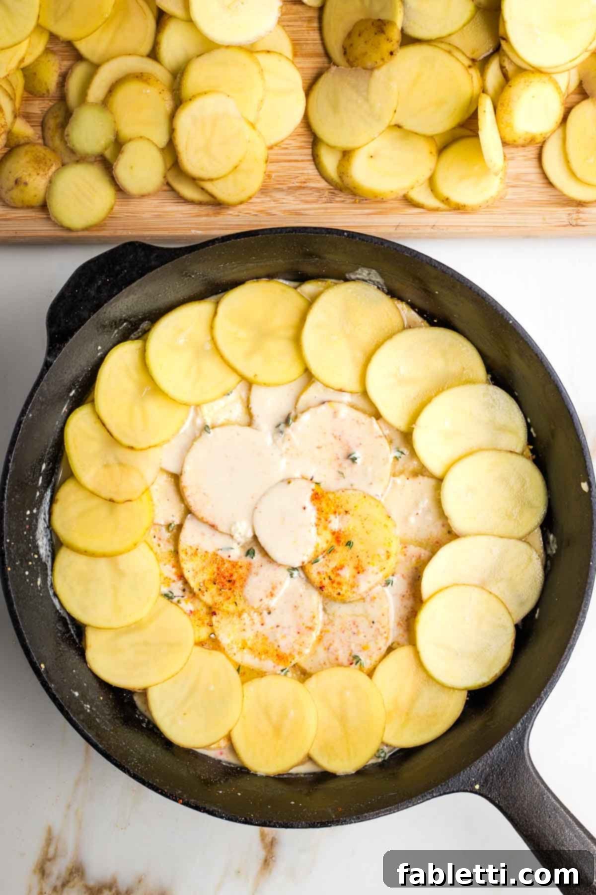 One-Pan Dairy-Free Gluten-Free Scalloped Potatoes 11 Multiple delicious layers of thinly sliced potatoes, creamy white sauce, fresh herbs, and savory spices beautifully stacked in a cast iron skillet, ready to be baked into dairy-free scalloped potatoes.