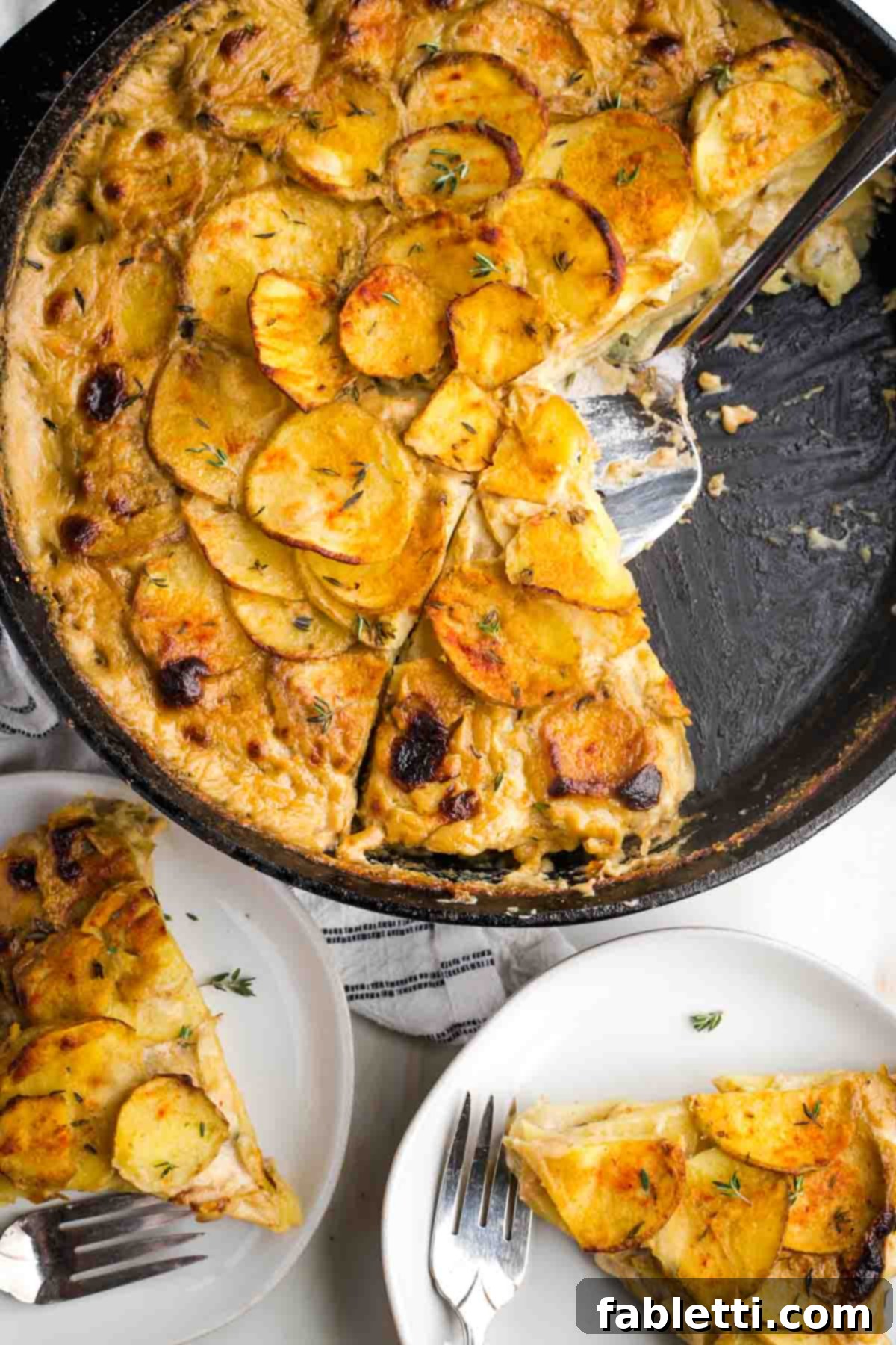 One-Pan Dairy-Free Gluten-Free Scalloped Potatoes 16 A beautifully presented skillet of dairy-free scalloped potatoes alongside two plates holding triangular slices, showcasing its versatility for serving.