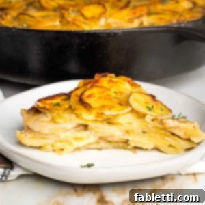 One-Pan Dairy-Free Gluten-Free Scalloped Potatoes 17 A side view of a perfectly baked slice of scalloped potatoes, golden brown and crisp on the top, with the simmering skillet of potatoes in the background.