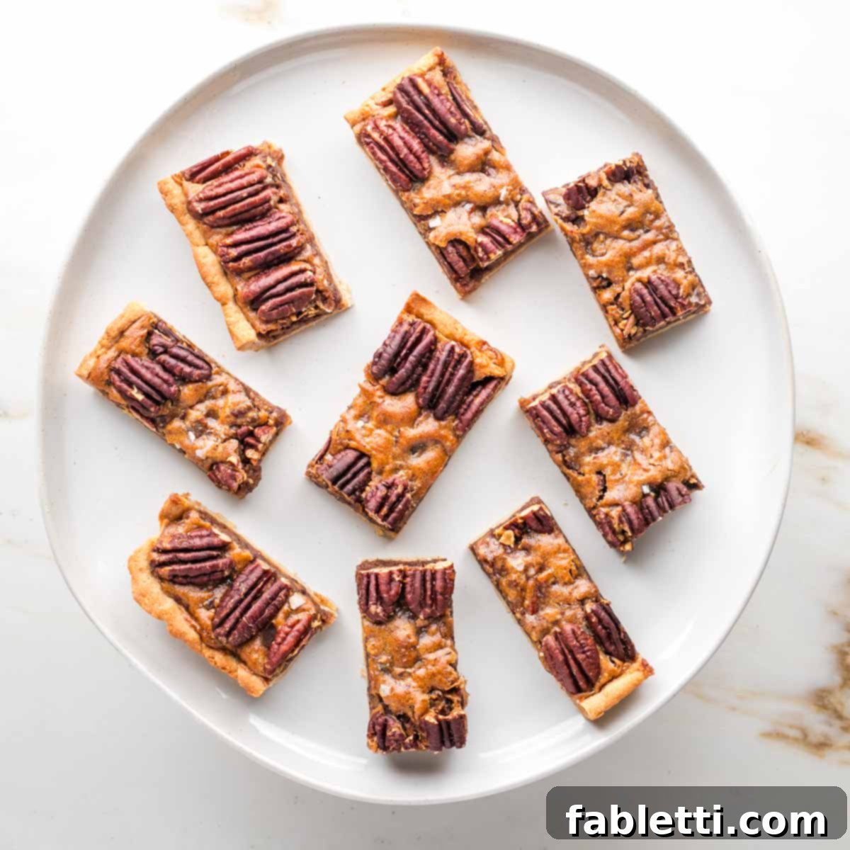 Naturally Sweetened Vegan Pecan Pie Bars 3 Rectangular slices of pecan pie bars on a round plate.