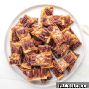 Naturally Sweetened Vegan Pecan Pie Bars 24 Plate piled with pecan pie bars, with a pie crust, caramel layer and pecan halves decorating the top.