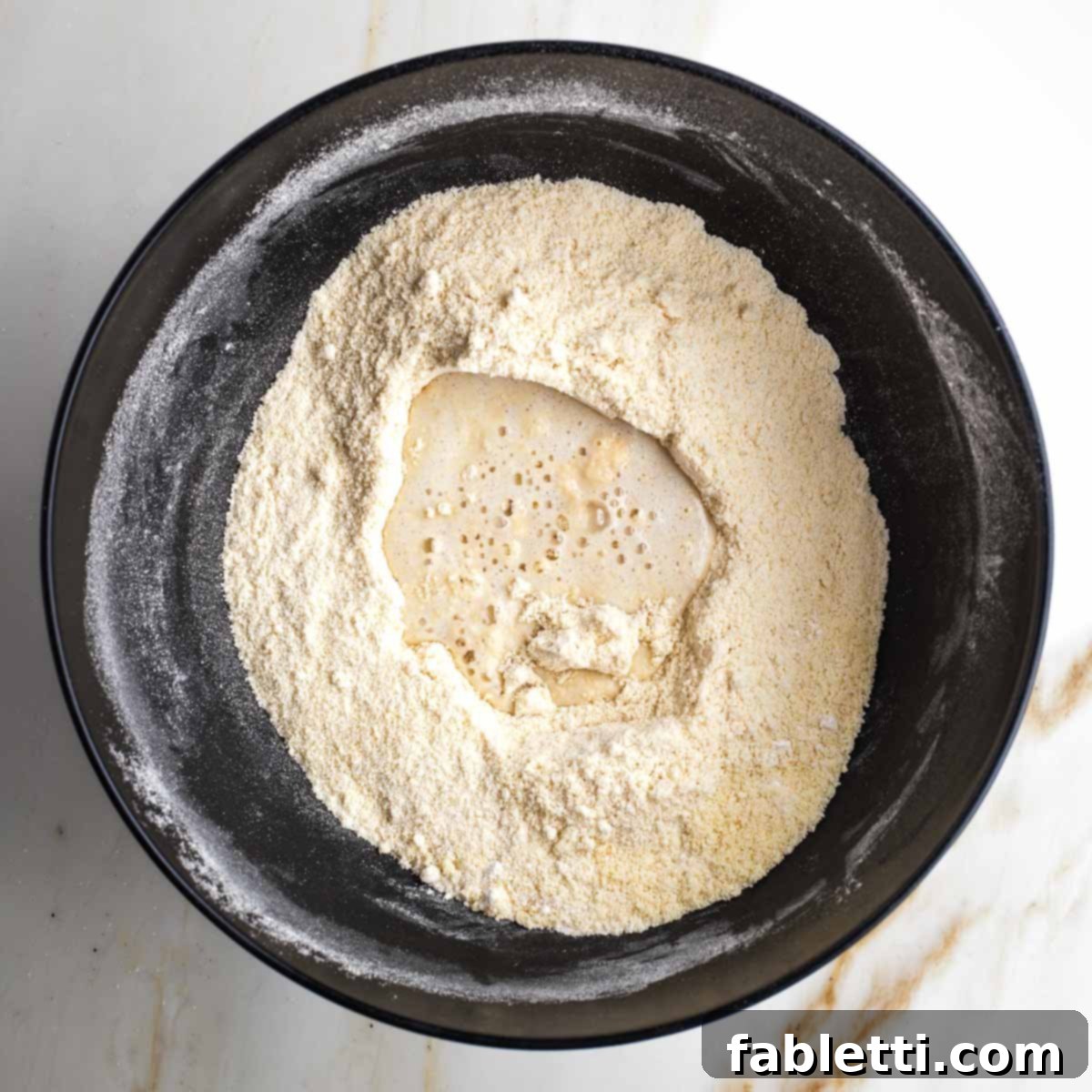 Naturally Sweetened Vegan Pecan Pie Bars 5 Milk mixture poured onto flour mixture in a black bowl.