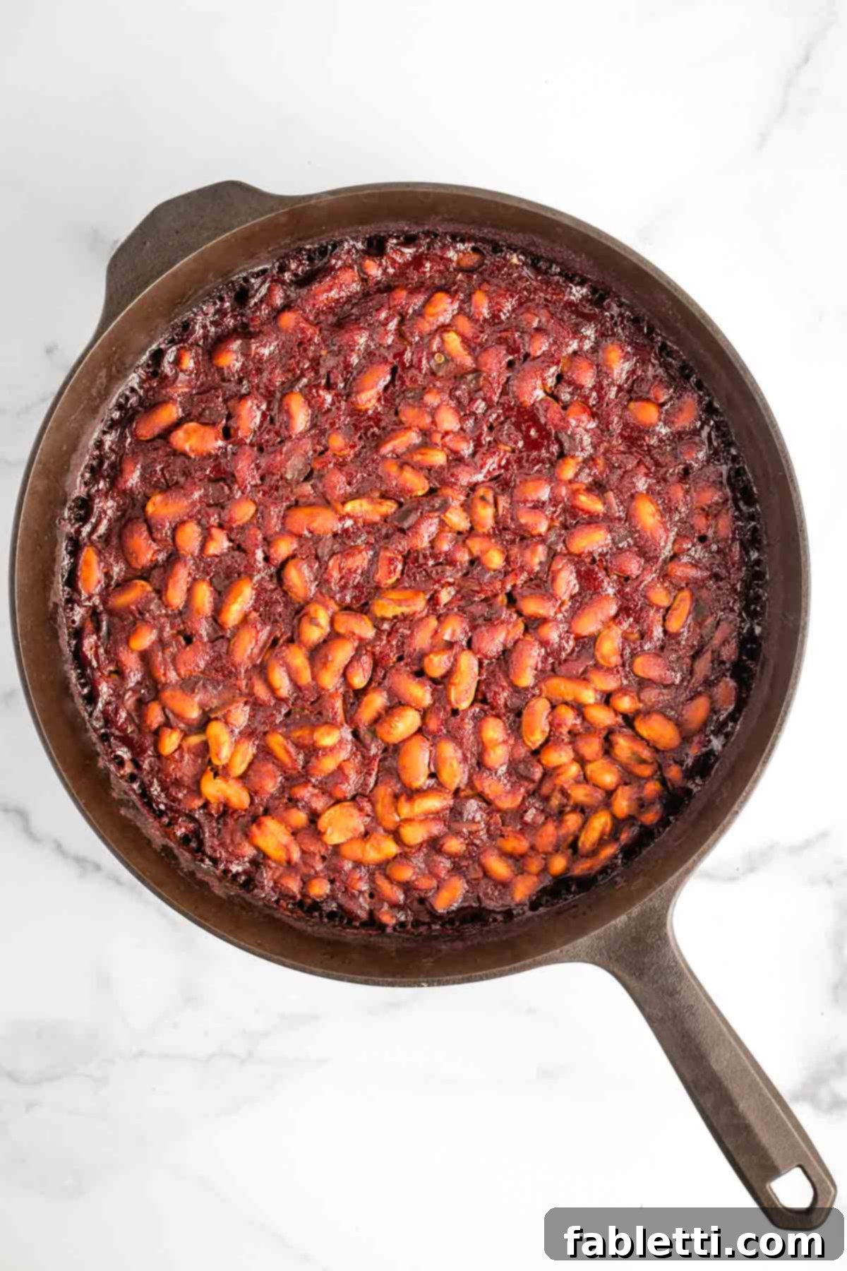 Effortless Skillet Plant-Based BBQ Beans 15 A bubbling cast iron skillet brimming with thick, rich BBQ baked beans, radiating warmth and ready to be served.