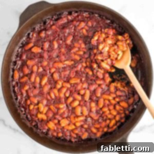 Effortless Skillet Plant-Based BBQ Beans 16 Baked beans in a cast iron skillet with wooden spoon.